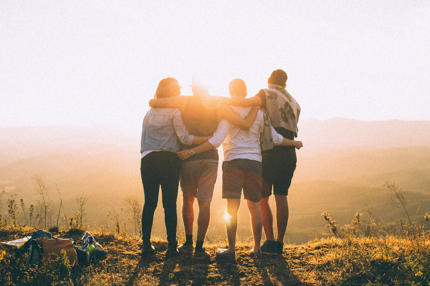 Group of people hugging each other. No faces. Photo by Helena Lopes on Unsplash